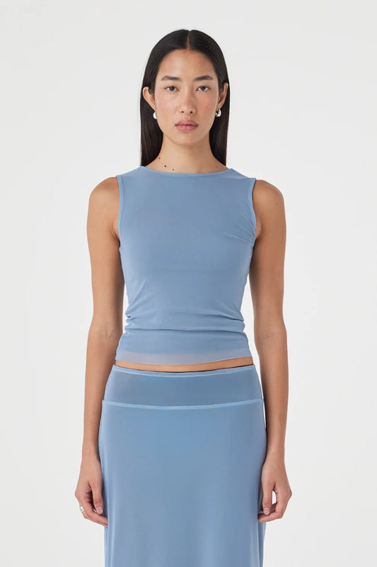 Close-up front view of the pale blue sleeveless reversible top with a high boat neckline and fitted silhouette, paired with the matching pale blue maxi skirt against a clean white studio background.
