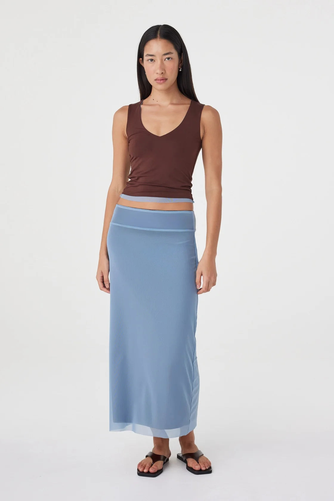 Front view of the espresso side of the reversible sleeveless top with a V-neckline, styled with the pale blue maxi skirt and black sandals against a white studio background.