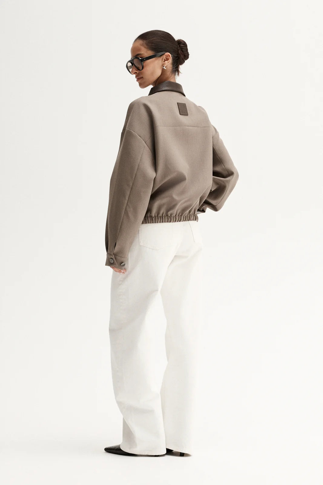 Person wearing a beige sweater and white pants on a white background
