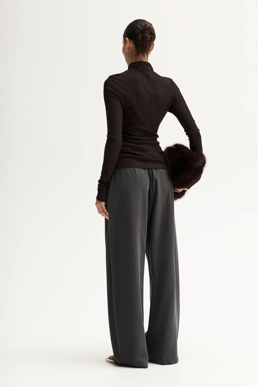 Person wearing a black long-sleeve top and gray wide-leg pants on a white background