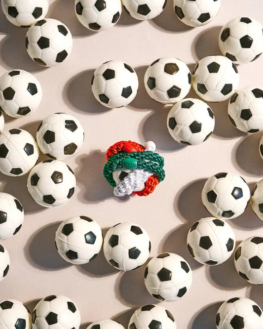 Forrest Green woven hair tie styled with colourful hair ties among miniature black and white soccer balls.