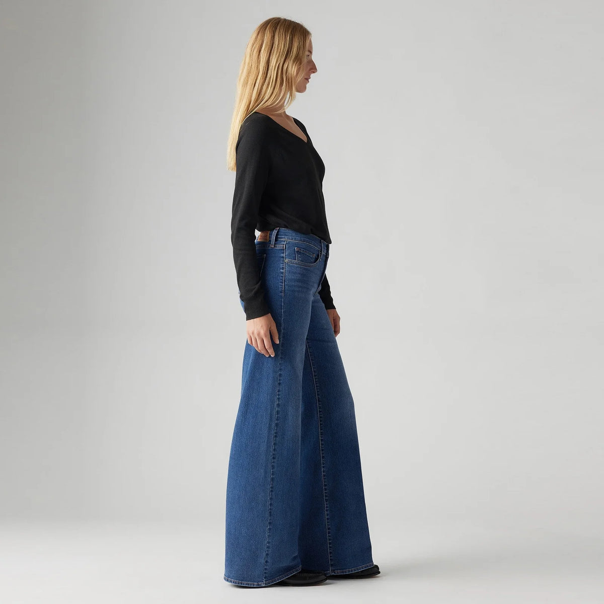 Model wearing the Levi's 318 Shaping Wide Leg Jeans in the Clever Girl wash, showing the high-rise fit and flared wide-leg silhouette in a side view.