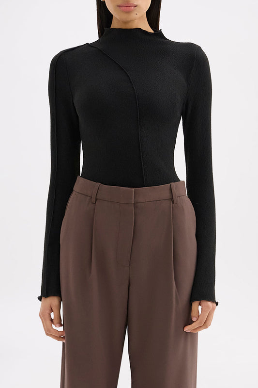 Close front view of the black long sleeve top showing the raised neckline and curved stitching detail.