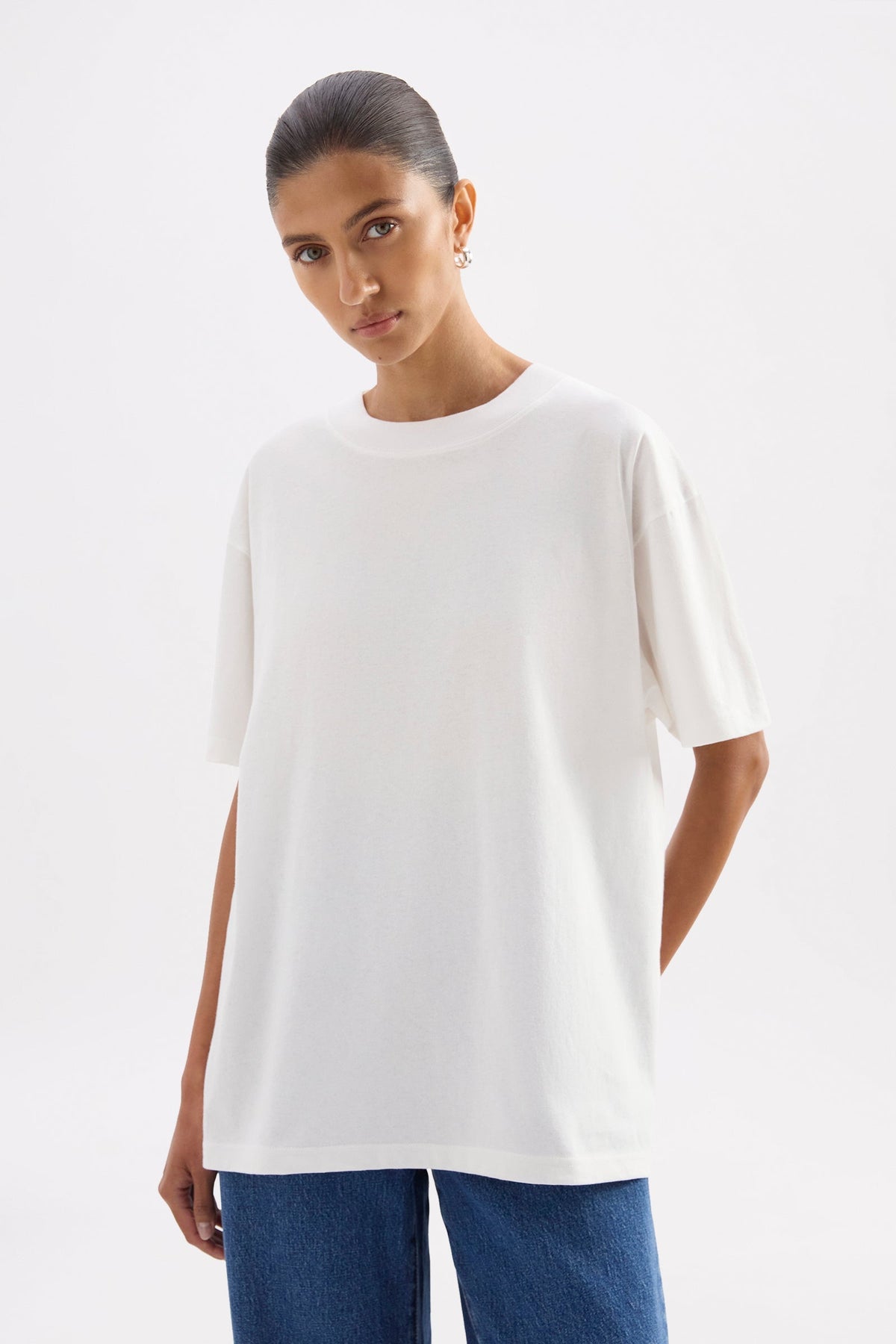 Upper-body front view of the white boyfriend tee styled with blue jeans against a minimal studio background.