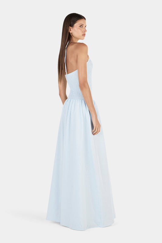 A rear three-quarter view showing the open back, thin halter strap, shirred bodice and gathered maxi skirt.