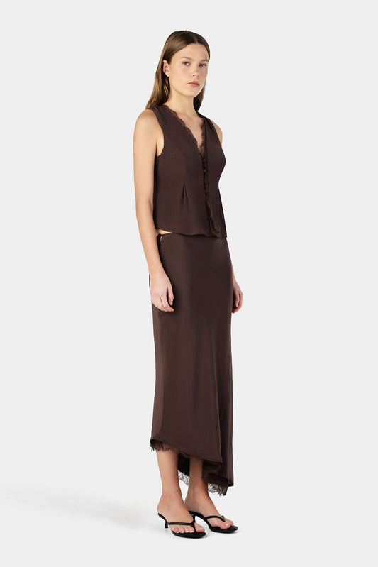 A woman wears a chocolate brown sleeveless top with a matching midi skirt in an angled full-length view.