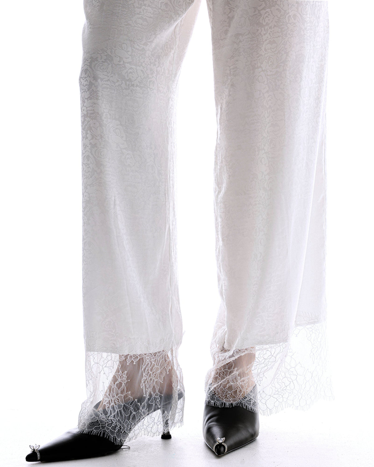 The Tales Frida Lace Hem Floral Pants in White — the Tales Frida Lace Hem Floral Pants offer an elevated take on relaxed tailoring with delicate lace trim detailing and an effortless silhouette.