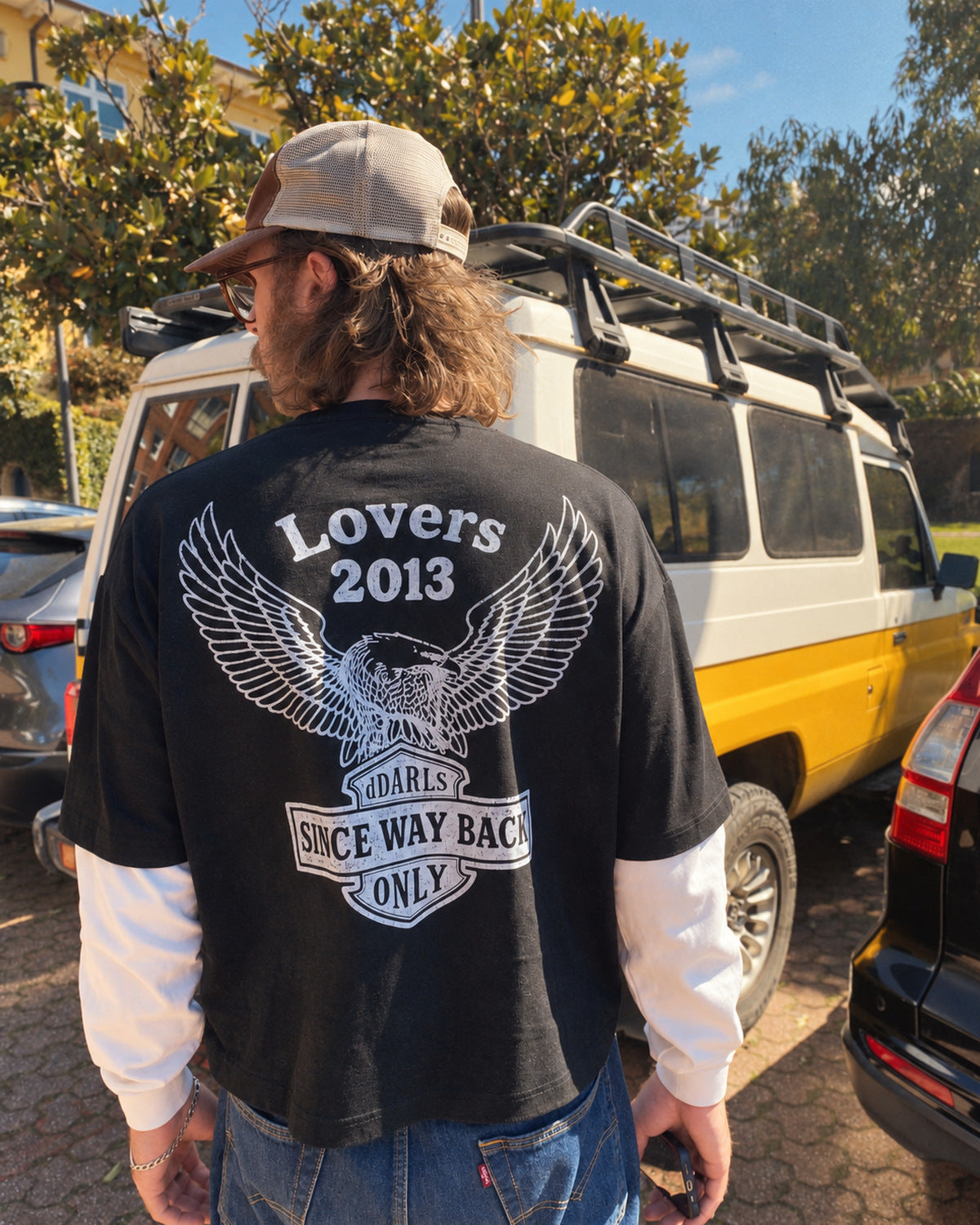 dDARL Lovers Layered Tee in Black, worn from behind by a man on a street, showing the eagle back graphic