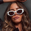 Model wearing the 180EYEWEAR 'Rufus' sunglasses in pearl white, close-up lifestyle shot against a dark grey background.