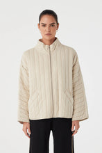 Woman wearing a beige quilted jacket on a white background