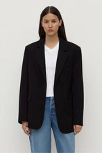 Person wearing a black blazer over a white shirt and blue jeans on a white background