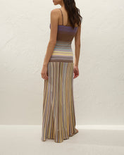 Woman wearing a long, striped dress with a white background
