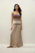 Woman wearing a striped top and long skirt against a white background