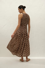 Woman wearing a brown polka dot dress against a white background