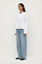 Person wearing a white long-sleeve shirt and light blue jeans on a white background