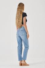 Woman wearing light blue jeans and a black top on a white background
