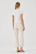 Person wearing a white t-shirt and beige pants on a plain background