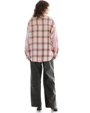 Person wearing a plaid shirt and dark pants on a white background