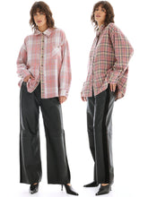 Two models wearing oversized pink and beige plaid button-up shirts with black wide-leg pants and black pointed heels, shown against a plain white studio background.