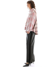 Person wearing a plaid shirt and black pants on a white background