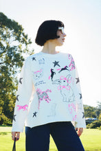 Person wearing a white sweater with colorful animal illustrations outdoors