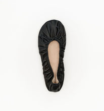 A single black leather ballet flat with a gathered bow detail on the toe, shown from a top-down view on a clean white background.