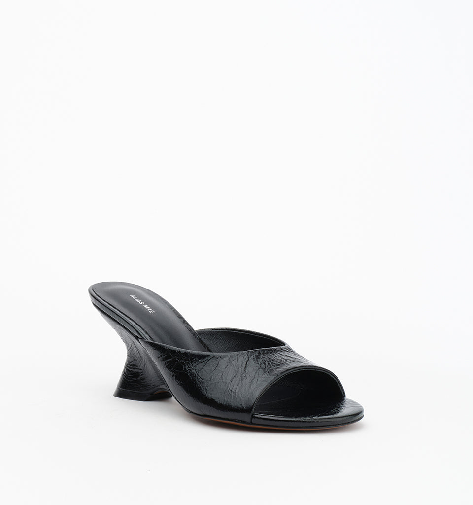 Three-quarter front view of the black crinkle leather mule highlighting the open toe and curved wedge heel.