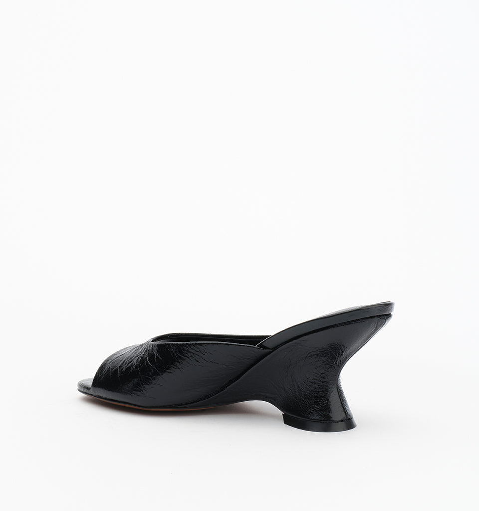 Rear side view of the black leather mule showing the open-back design and sculptural wedge heel.