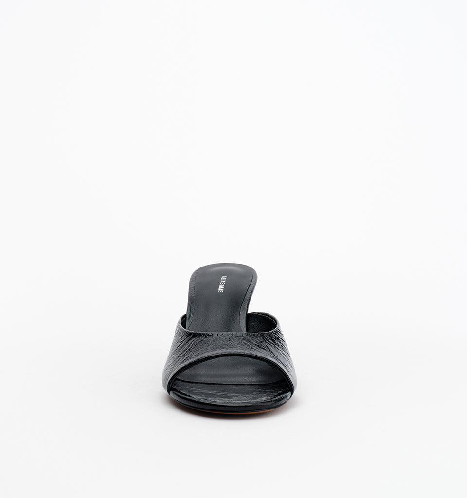 Front view of the black open-toe mule showing the wide crinkle leather strap and rounded toe shape.