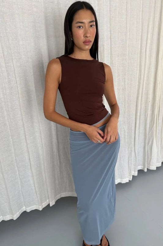 Pale blue side of the reversible maxi skirt styled with an espresso sleeveless top in a relaxed front pose against soft white curtains.