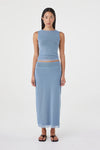 Front view of the pale blue reversible maxi skirt styled with a matching pale blue sleeveless top and black sandals against a clean white studio background.
