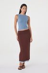 Front view of the espresso side of the reversible maxi skirt styled with a pale blue sleeveless top and black sandals against a white studio background.