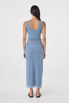 Back view of the pale blue reversible maxi skirt styled with a matching pale blue sleeveless top and black sandals against a clean white studio background.
