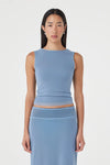 Close-up front view of the pale blue sleeveless reversible top with a high boat neckline and fitted silhouette, paired with the matching pale blue maxi skirt against a clean white studio background.