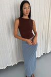 Espresso sleeveless reversible top styled with the pale blue maxi skirt, shown in a relaxed angled pose in front of soft white curtains.