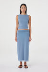 Front view of the pale blue sleeveless reversible top with a fitted waist, styled with the matching pale blue maxi skirt and black sandals against a white studio background.