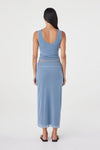 Back view of the pale blue reversible top showing the deep V-shaped back neckline, styled with the matching pale blue maxi skirt against a white studio background.