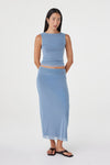 Full-length front view of the pale blue sleeveless top and matching maxi skirt, with the model standing with her hands behind her back in a clean white studio.