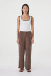 Full-length front view of the cream fitted tank with teal contrast trim, styled with brown wide-leg wrap pants and black sandals against a clean white studio background.