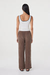 Back view of the cream fitted tank with teal contrast trim at the neckline and straps, styled with brown wide-leg wrap pants and black sandals against a clean white studio background.