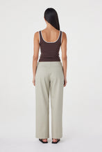 Model wearing the espresso fitted tank with cream tailored trousers, showing the square scoop back, wide shoulder straps, contrast cream edging and close-to-body silhouette in a full-length back view.