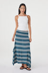 Front angled view of the teal striped maxi skirt showing its asymmetric draped hem, styled with a white sleeveless top and black sandals in a white studio.