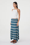 Three-quarter side view of the teal striped maxi skirt styled with a white sleeveless top and black sandals against a minimal white studio background.