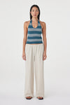 Full-length front view of the teal striped halter top paired with cream wide-leg pants and black sandals against a clean white studio background.