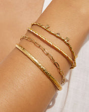 Gold bracelets on a wrist with a neutral background