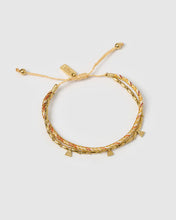 Gold braided bracelet with small charms on a light gray background