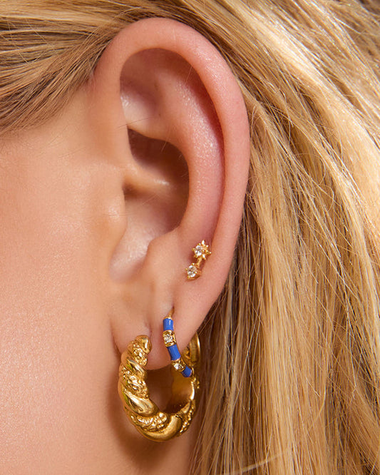 Arms Of Eve Papaya Enamel Huggies Blueberry worn in a layered gold earring stack.