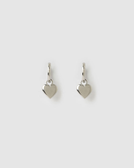 Arms Of Eve Treasure Silver Earrings with polished heart charms on a light background.