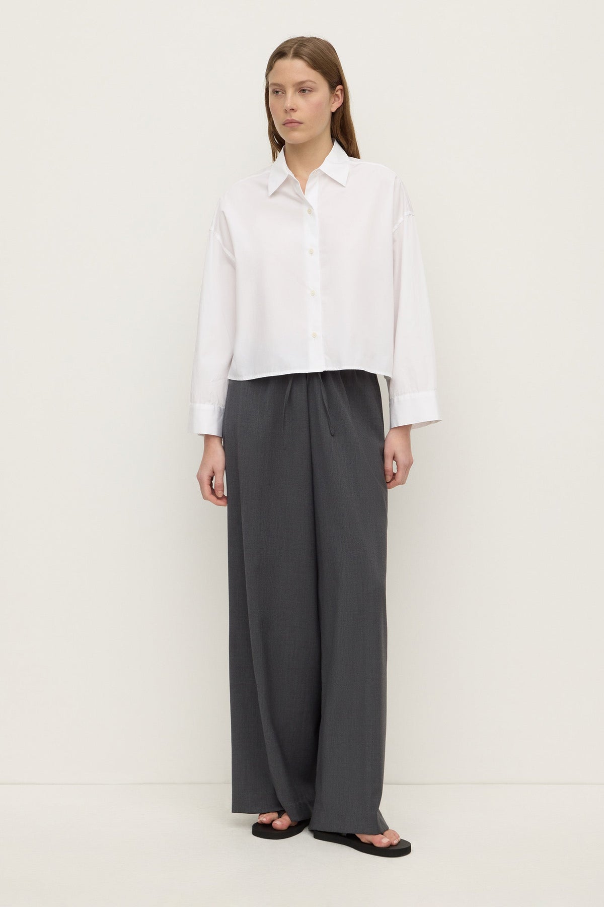 Front view of a white cropped shirt with a pointed collar, button closure and relaxed boxy silhouette.