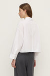 Back view of a white cropped shirt showing the pointed collar, straight back panel and long sleeves.